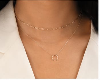 Layered gold necklaces at the collarbone